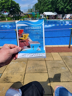 Flyer in der Hand vor Schwimmbecken